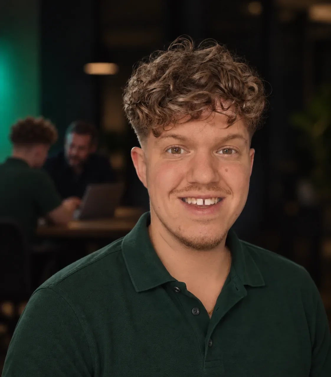 John Schreve in een donkergroene polo, op de achtergrond aan tafel met een ondernemer